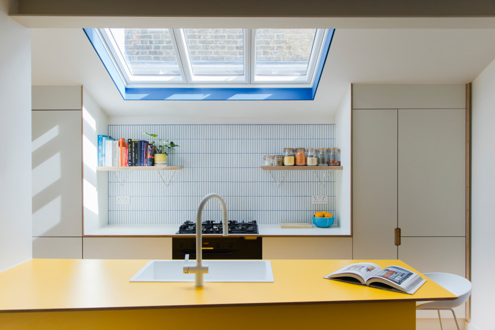 Inspiration for a scandi galley open plan kitchen in London with flat-panel cabinets, white cabinets and an island.