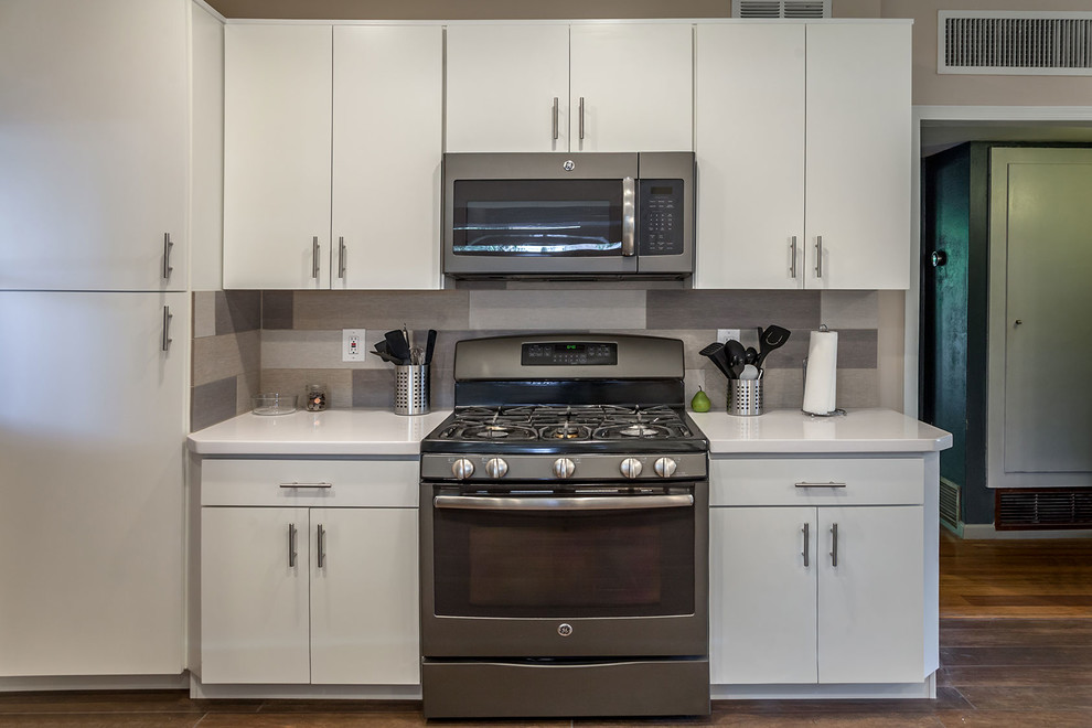 Transitional u-shaped porcelain tile open concept kitchen photo in Phoenix with a farmhouse sink, shaker cabinets, white cabinets, quartz countertops, multicolored backsplash, porcelain backsplash, stainless steel appliances and an island