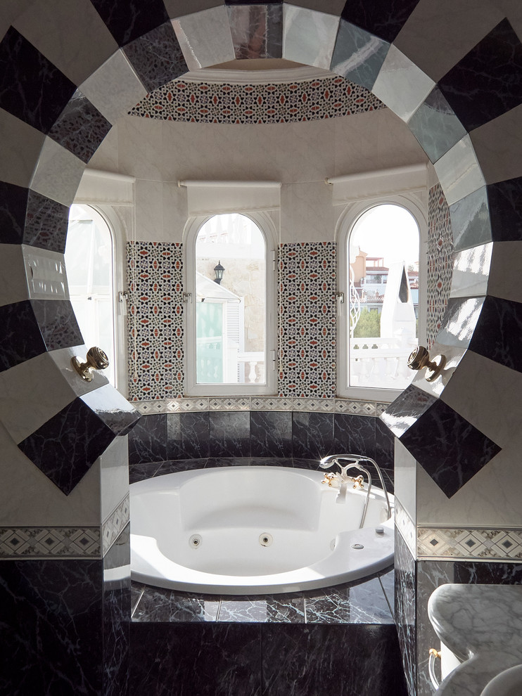 Inspiration for a mid-sized mediterranean master bathroom in Malaga with a hot tub, black and white tile, ceramic tile, ceramic floors, marble benchtops and multi-coloured walls.