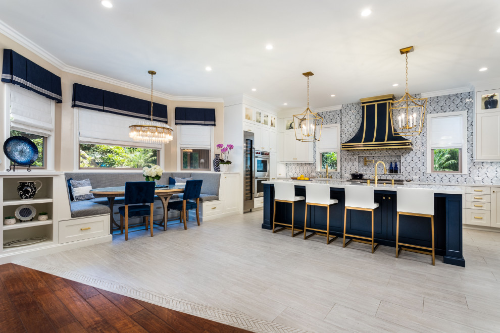 Photo of a mid-sized contemporary open plan kitchen in Los Angeles with a farmhouse sink, shaker cabinets, white cabinets, marble benchtops, multi-coloured splashback, glass tile splashback, stainless steel appliances, travertine floors, with island, grey floor and white benchtop.