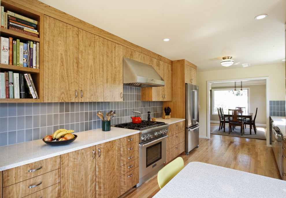 Photo of a transitional galley eat-in kitchen in Portland with recycled glass benchtops, stainless steel appliances, a farmhouse sink, flat-panel cabinets, medium wood cabinets, blue splashback and ceramic splashback.