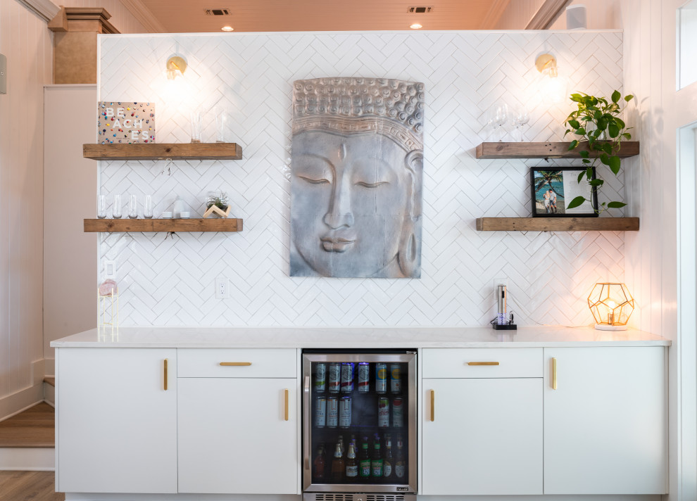 Photo of a mid-sized modern l-shaped home bar in Other with an undermount sink, flat-panel cabinets, white cabinets, quartzite benchtops, white splashback, engineered quartz splashback, light hardwood floors, brown floor and white benchtop.