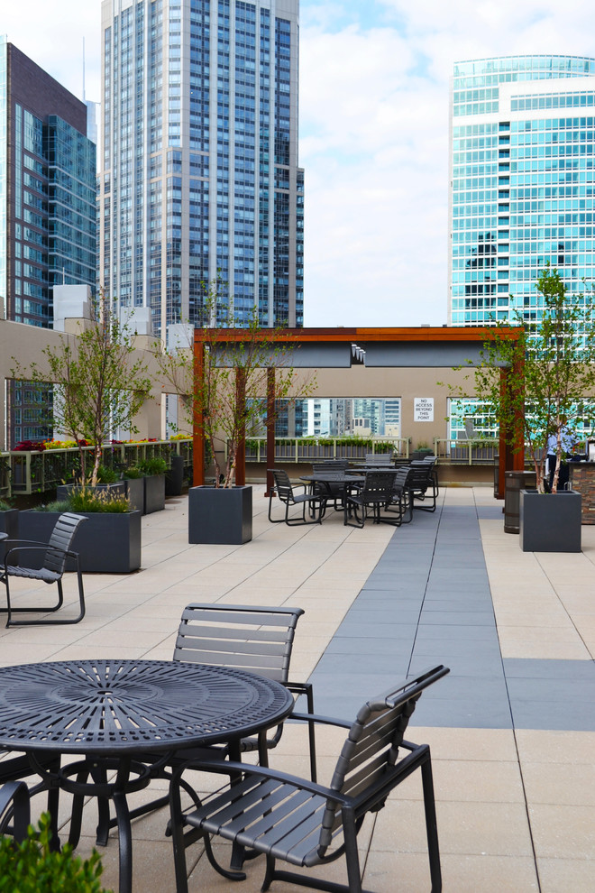 This is an example of an expansive contemporary rooftop deck in Chicago with an outdoor kitchen and a pergola.