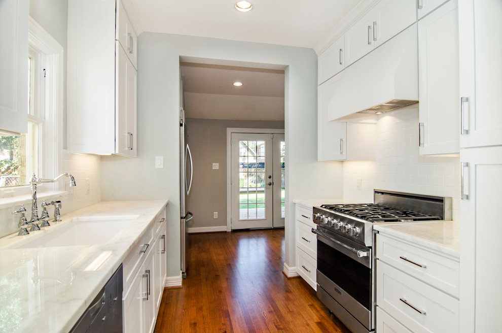 Inspiration for a transitional galley eat-in kitchen remodel in Dallas with an undermount sink, shaker cabinets, white cabinets, marble countertops, white backsplash, subway tile backsplash and stainless steel appliances