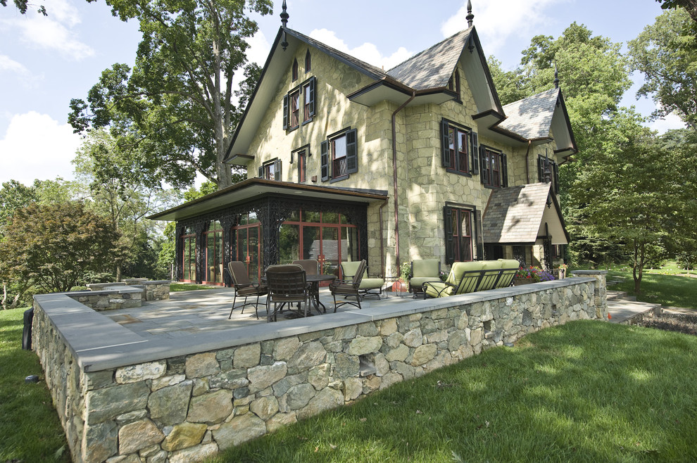 Expansive traditional three-storey green house exterior in Philadelphia with stone veneer and a tile roof.