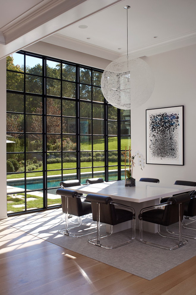 Contemporary dining room in New York with white walls and light hardwood floors.