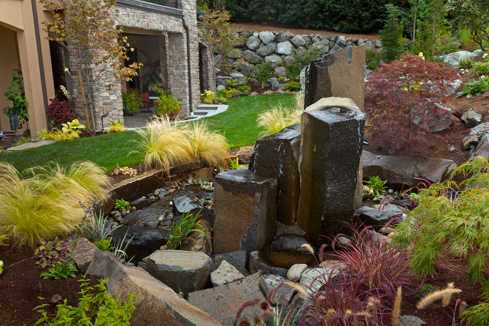 This is an example of a large contemporary backyard full sun garden in Seattle with a water feature.