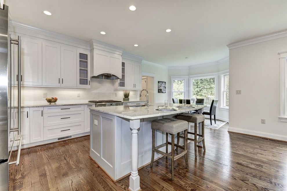 Inspiration for a large transitional l-shaped medium tone wood floor eat-in kitchen remodel in DC Metro with beaded inset cabinets, white cabinets, granite countertops, white backsplash, stainless steel appliances, an island and a drop-in sink