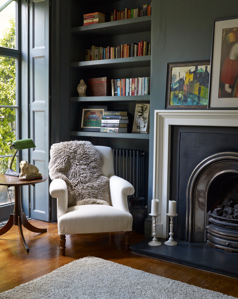 Traditional home office in London with blue walls, medium hardwood floors, a standard fireplace and a library.