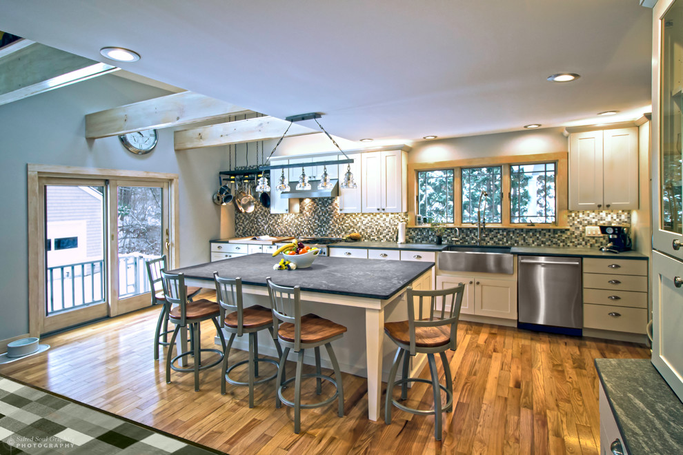 Open concept kitchen - large rustic l-shaped light wood floor open concept kitchen idea in Burlington with an undermount sink, shaker cabinets, white cabinets, soapstone countertops, multicolored backsplash, glass tile backsplash, stainless steel appliances and an island