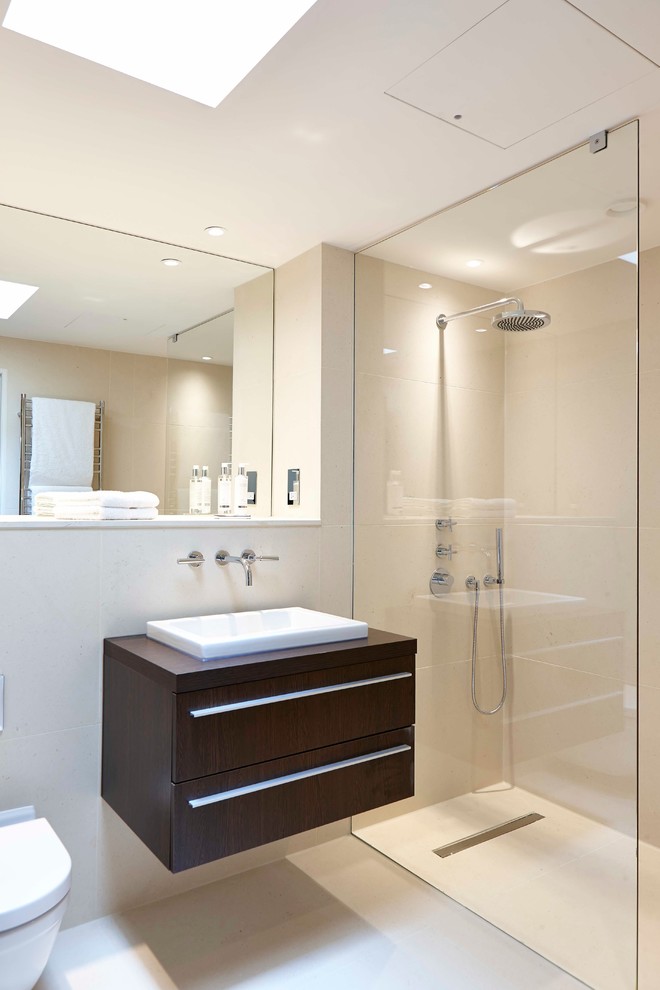Design ideas for a contemporary bathroom in Berkshire with a drop-in sink, flat-panel cabinets, dark wood cabinets, a curbless shower, a wall-mount toilet and beige tile.