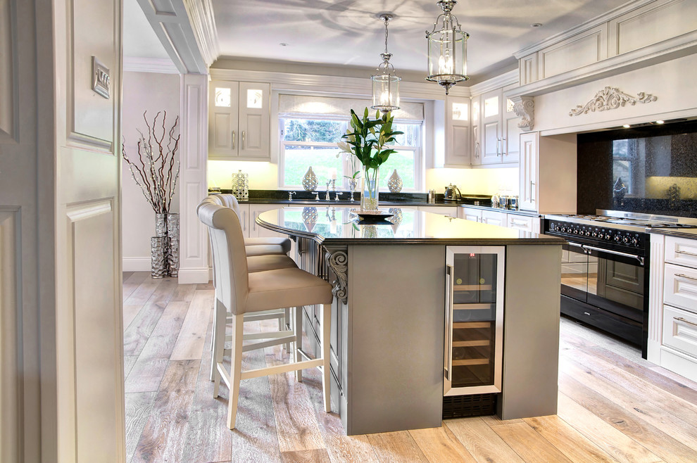 This is an example of a large traditional u-shaped eat-in kitchen in Other with an integrated sink, raised-panel cabinets, white cabinets, granite benchtops, black splashback, stainless steel appliances, medium hardwood floors, with island, brown floor and black benchtop.