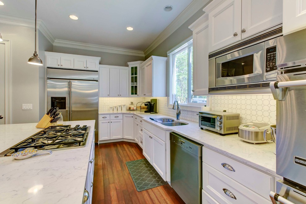 Small transitional galley eat-in kitchen in Raleigh with a double-bowl sink, recessed-panel cabinets, white cabinets, quartzite benchtops, white splashback, ceramic splashback, stainless steel appliances, medium hardwood floors and with island.