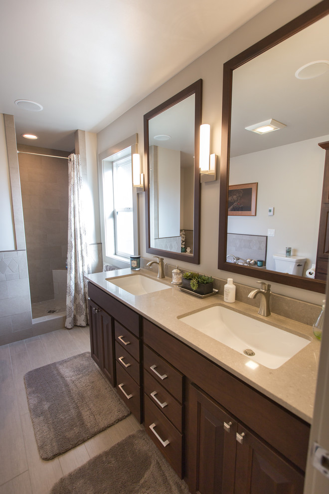 Photo of a mid-sized transitional master bathroom in Other with raised-panel cabinets, dark wood cabinets, an undermount tub, grey walls, porcelain floors, an undermount sink, engineered quartz benchtops, an alcove shower, grey floor, a shower curtain, a two-piece toilet, gray tile and porcelain tile.