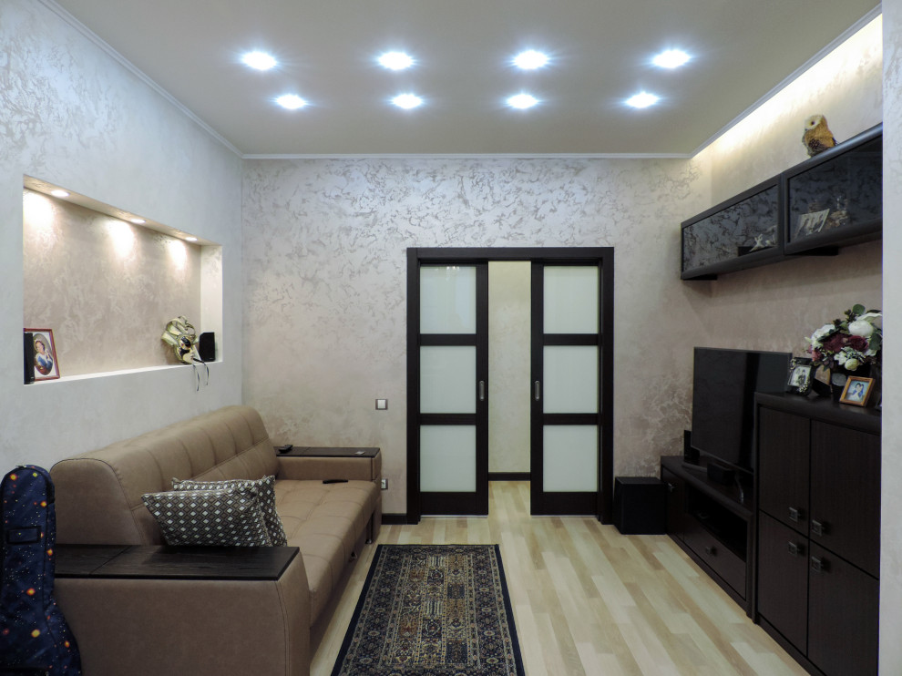 Ejemplo de salón tradicional renovado de tamaño medio sin chimenea con paredes beige, suelo laminado, televisor independiente, suelo beige y bandeja