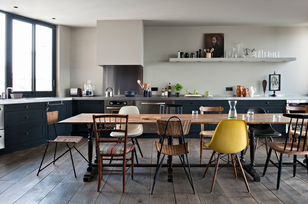 Photo of a large industrial l-shaped open plan kitchen in Paris with black cabinets, stainless steel benchtops, metallic splashback, metal splashback, stainless steel appliances, dark hardwood floors and no island.