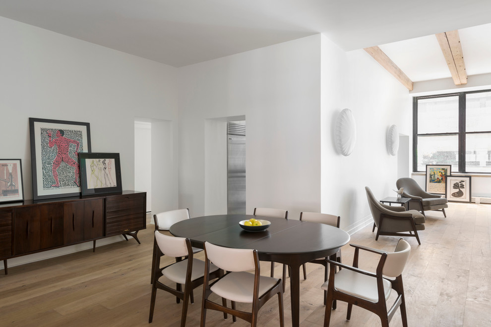 This is an example of a contemporary open plan dining in New York with white walls and light hardwood floors.
