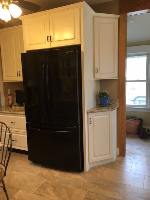 Mid-sized transitional galley porcelain tile eat-in kitchen photo in Boston with an undermount sink, raised-panel cabinets, white cabinets, granite countertops, black appliances and an island