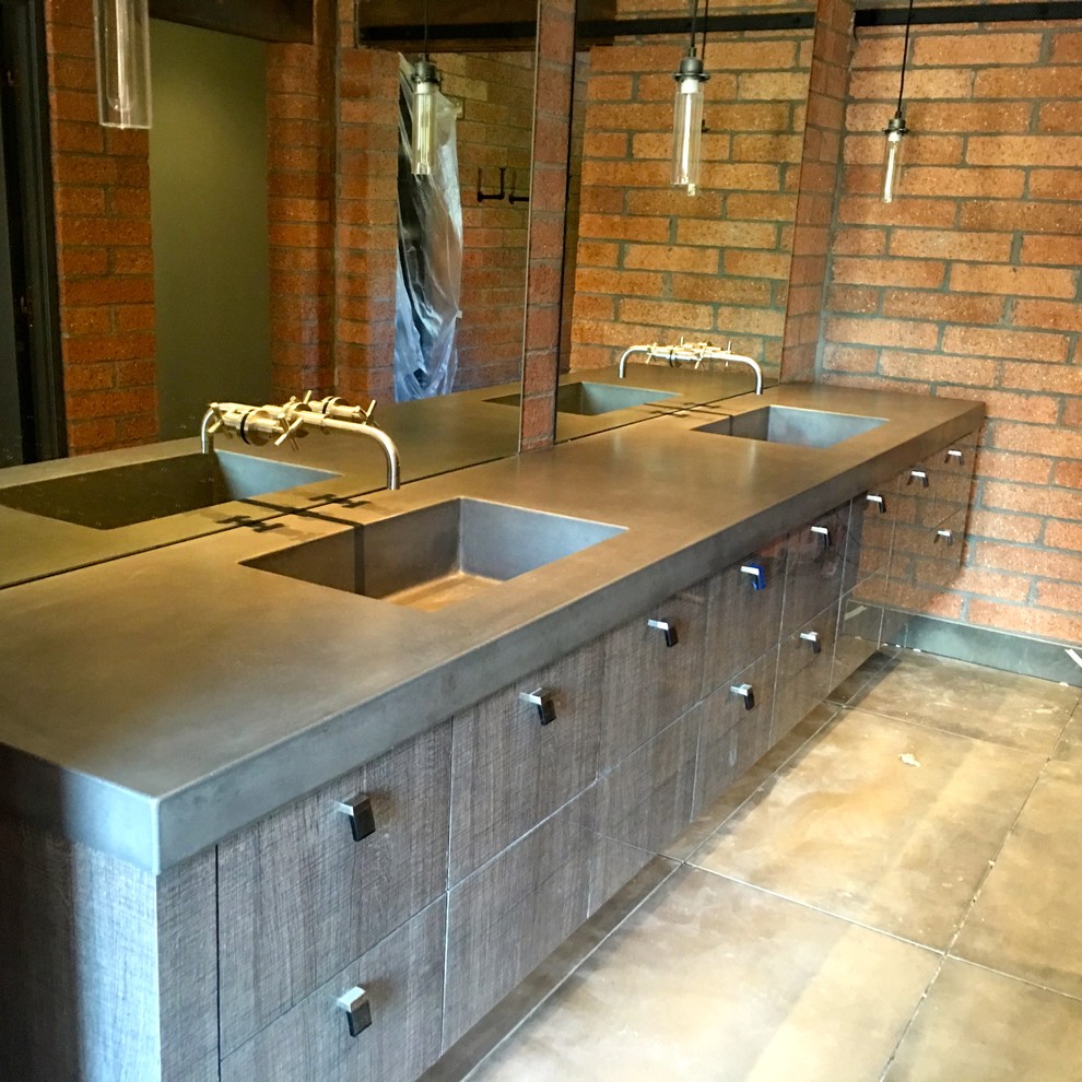 This is an example of a mid-sized industrial master bathroom in Phoenix with flat-panel cabinets, distressed cabinets, concrete floors, grey floor, red walls, an integrated sink and concrete benchtops.