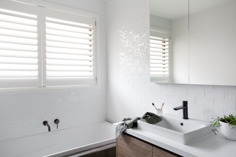 Источник вдохновения для домашнего уюта: маленькая ванная комната в современном стиле с плоскими фасадами, светлыми деревянными фасадами, накладной ванной, душем в нише, белой плиткой, плиткой кабанчик, белыми стенами, полом из керамической плитки, накладной раковиной, столешницей из ламината, серым полом, душем с распашными дверями, белой столешницей, нишей, тумбой под одну раковину и встроенной тумбой для на участке и в саду