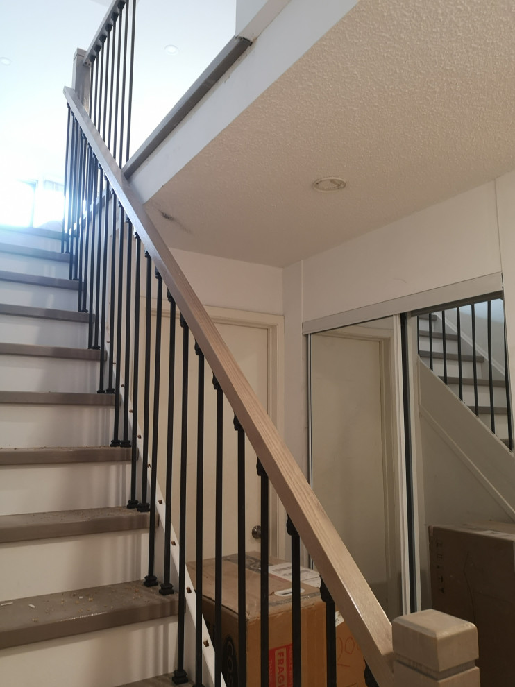 Photo of a mid-sized modern wood l-shaped staircase in Toronto with wood risers, glass railing and panelled walls.
