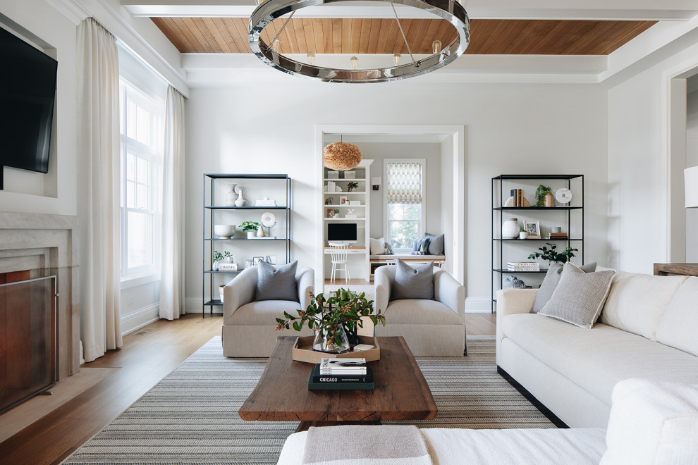 Inspiration for a large transitional open concept family room in Chicago with white walls, light hardwood floors, a standard fireplace, a stone fireplace surround, a wall-mounted tv, brown floor and exposed beam.