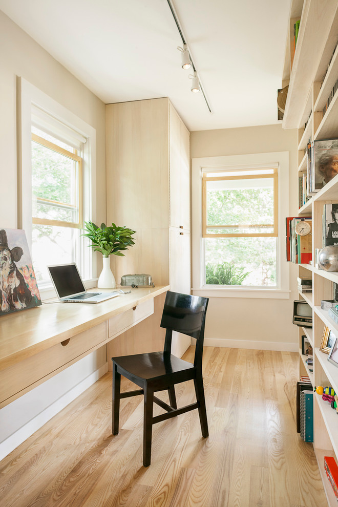 Photo of a contemporary home office in Portland Maine with a built-in desk and beige floor.