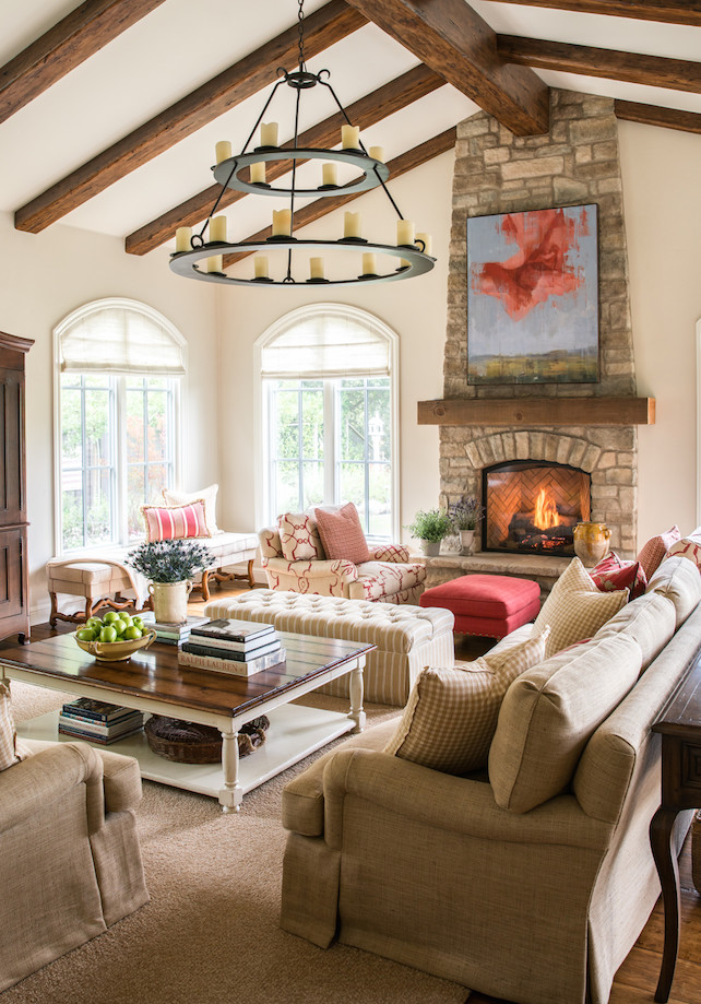 This is an example of a mid-sized mediterranean open concept living room in San Francisco with beige walls, medium hardwood floors, a standard fireplace, a stone fireplace surround, a concealed tv and brown floor.
