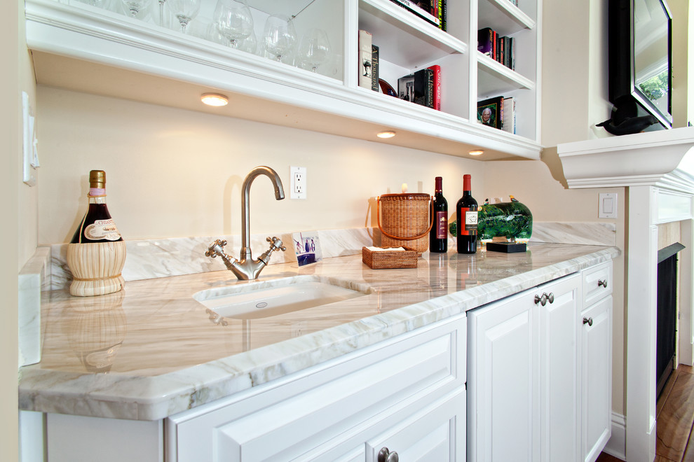 This is an example of a small traditional single-wall wet bar in Miami with an undermount sink, raised-panel cabinets, white cabinets, marble benchtops and dark hardwood floors.