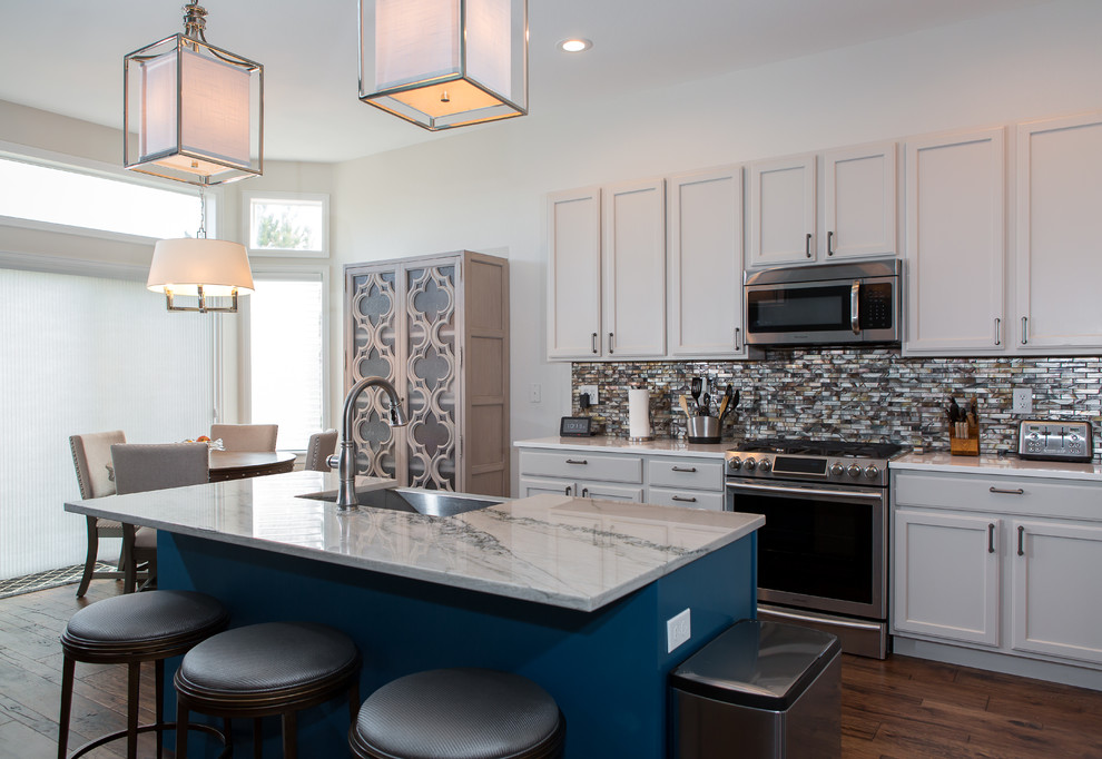 Mid-sized transitional l-shaped dark wood floor and brown floor open concept kitchen photo in Denver with a farmhouse sink, shaker cabinets, white cabinets, marble countertops, metallic backsplash, matchstick tile backsplash, paneled appliances, an island and gray countertops