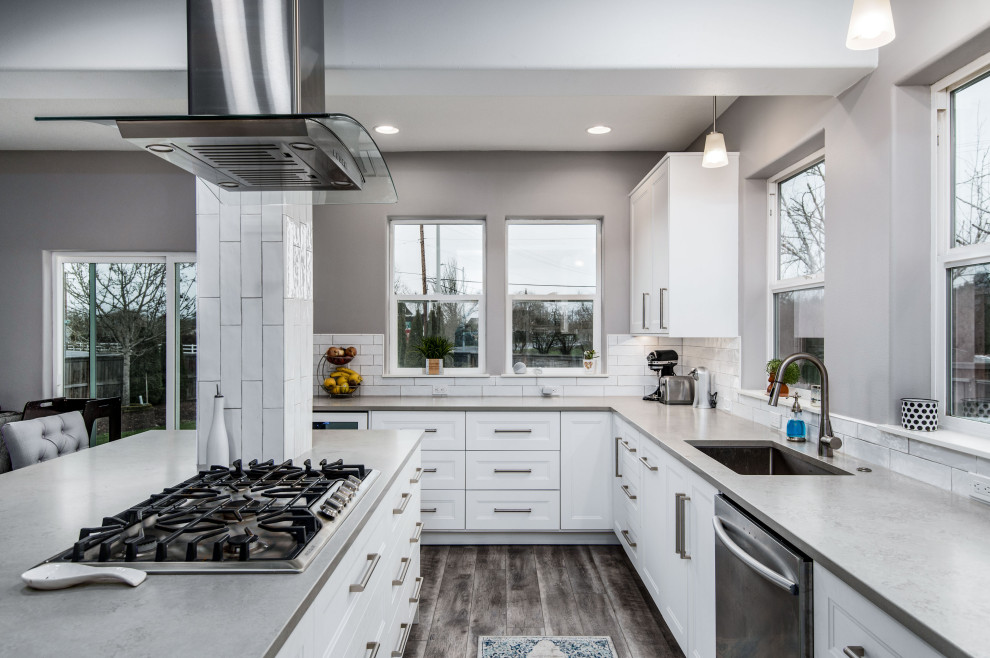 Eat-in kitchen - mid-sized transitional l-shaped vinyl floor and gray floor eat-in kitchen idea in Portland with an undermount sink, shaker cabinets, white cabinets, solid surface countertops, white backsplash, ceramic backsplash, stainless steel appliances, an island and gray countertops