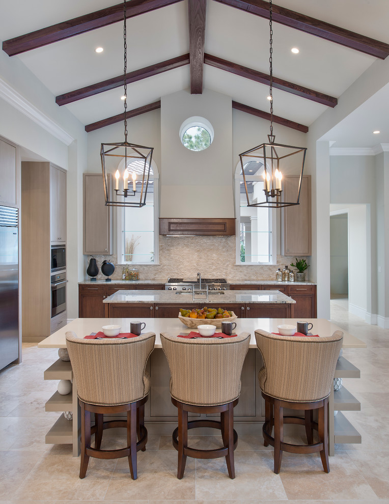 Photo of a large transitional l-shaped open plan kitchen in Tampa with a drop-in sink, marble benchtops, beige splashback, stone tile splashback, stainless steel appliances and multiple islands.