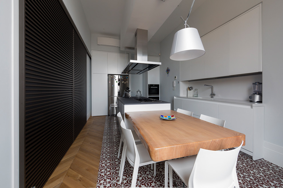 Design ideas for a contemporary kitchen in Naples with an integrated sink, flat-panel cabinets, white cabinets, white splashback, glass sheet splashback, stainless steel appliances, ceramic floors, with island, multi-coloured floor and grey benchtop.