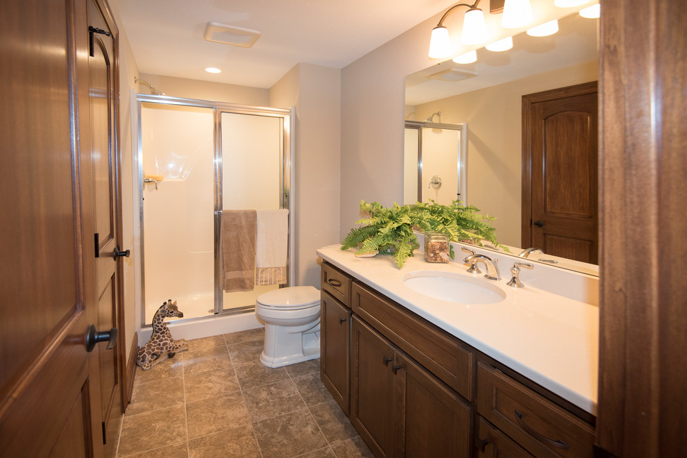 Mid-sized traditional 3/4 bathroom in Milwaukee with shaker cabinets, brown cabinets, an undermount tub, a shower/bathtub combo, a two-piece toilet, beige tile, beige walls, ceramic floors, an undermount sink, engineered quartz benchtops, brown floor and a sliding shower screen.