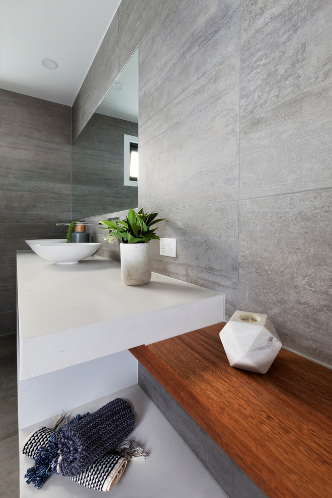 Mid-sized contemporary master bathroom in Melbourne with flat-panel cabinets, white cabinets, a freestanding tub, an alcove shower, a two-piece toilet, gray tile, cement tile, grey walls, concrete floors, a vessel sink and engineered quartz benchtops.