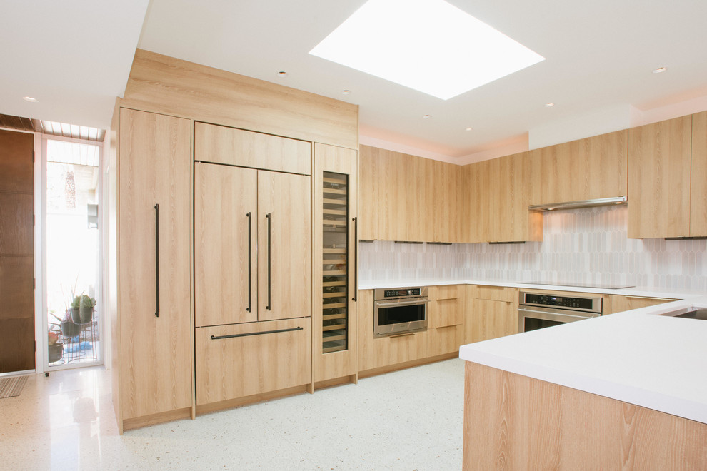 Foto på ett mellanstort funkis vit kök, med en undermonterad diskho, släta luckor, skåp i mellenmörkt trä, grått stänkskydd, stänkskydd i keramik, rostfria vitvaror, terrazzogolv och vitt golv
