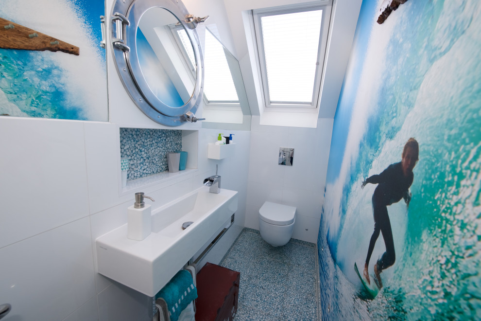 Источник вдохновения для домашнего уюта: маленькая ванная комната в современном стиле с открытым душем, инсталляцией, белой плиткой, керамической плиткой, белыми стенами, полом из галечной плитки, душевой кабиной, подвесной раковиной, синим полом, душем с распашными дверями, акцентной стеной и тумбой под одну раковину для на участке и в саду