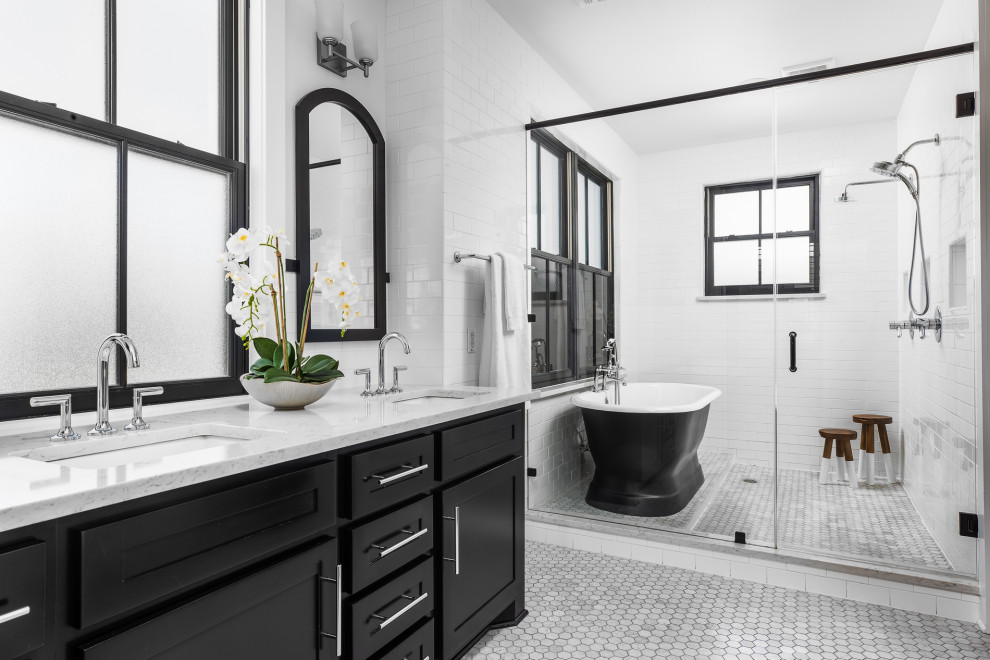 This is an example of a large transitional master bathroom in Austin with shaker cabinets, black cabinets, a freestanding tub, a double shower, white tile, ceramic tile, marble floors, an undermount sink, solid surface benchtops, grey floor, a hinged shower door, white benchtops, a double vanity, a freestanding vanity and white walls.