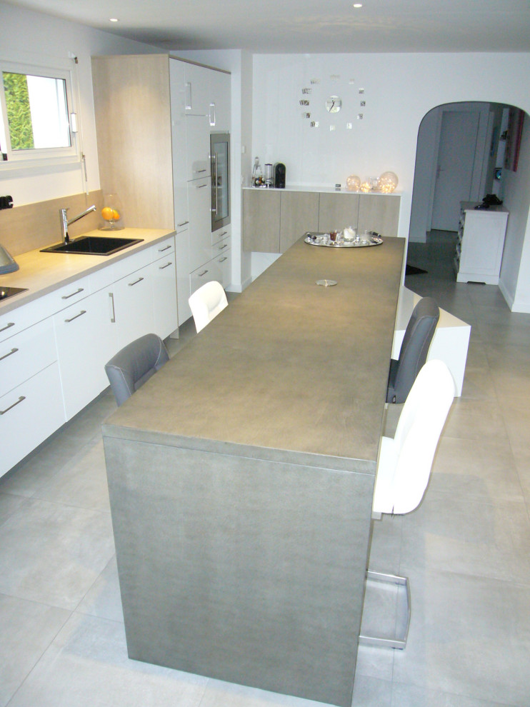 Photo of a large contemporary single-wall open plan kitchen in Nantes with a single-bowl sink, flat-panel cabinets, white cabinets, concrete benchtops, timber splashback, panelled appliances, ceramic floors, with island, grey floor and grey benchtop.