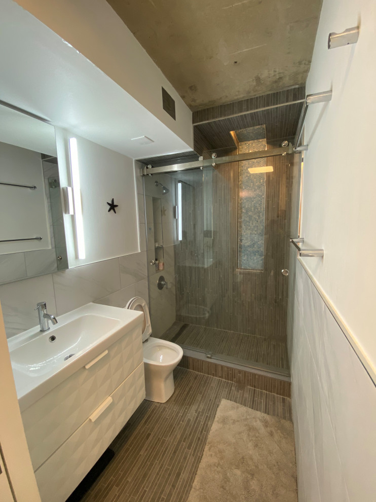 Источник вдохновения для домашнего уюта: маленькая ванная комната в стиле модернизм с плоскими фасадами, белыми фасадами, душем в нише, унитазом-моноблоком, серой плиткой, керамогранитной плиткой, белыми стенами, полом из керамогранита, душевой кабиной, монолитной раковиной, столешницей из искусственного камня, серым полом, душем с раздвижными дверями, белой столешницей, нишей, тумбой под одну раковину, подвесной тумбой и панелями на стенах для на участке и в саду