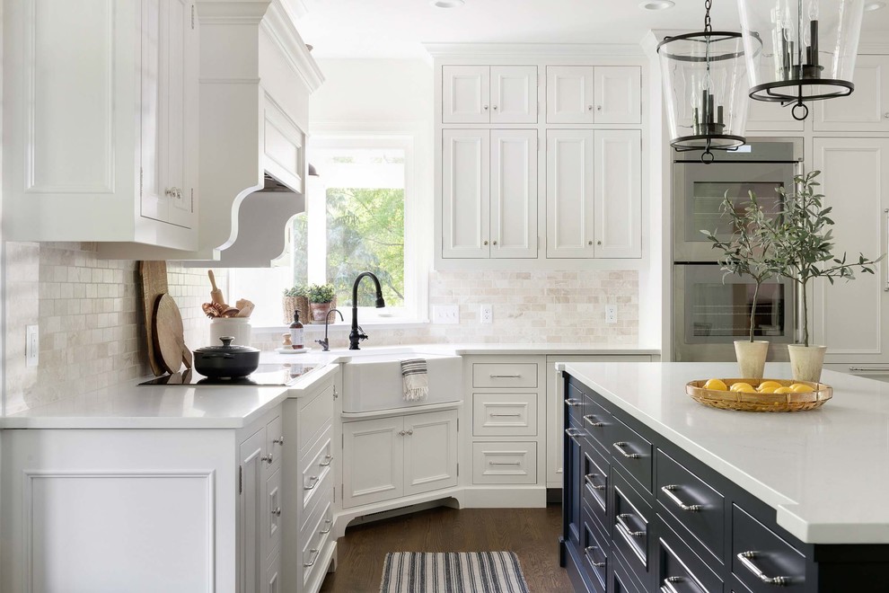 Country u-shaped eat-in kitchen in Minneapolis with a farmhouse sink, beaded inset cabinets, white cabinets, white splashback, dark hardwood floors, with island, brown floor and white benchtop.