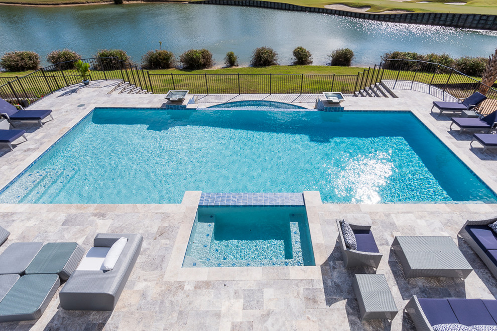 Large transitional backyard rectangular infinity pool in Orlando with natural stone pavers.