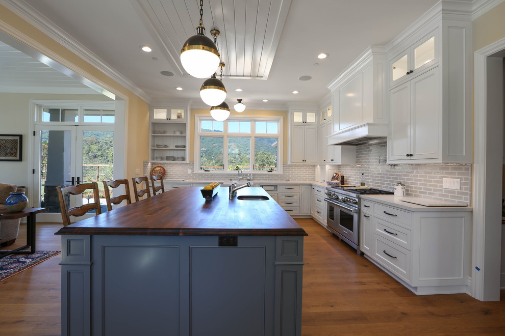 This is an example of a large traditional l-shaped open plan kitchen in San Francisco with beaded inset cabinets, white cabinets, quartz benchtops, white splashback, subway tile splashback, panelled appliances, medium hardwood floors and with island.