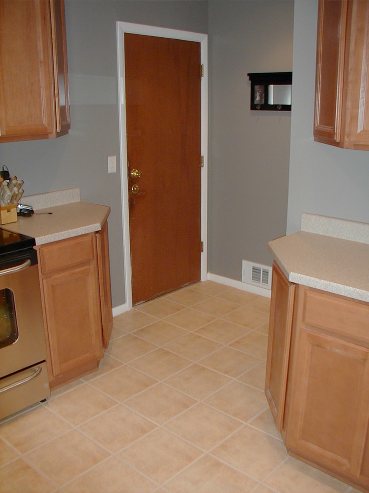 Enclosed kitchen - mid-sized galley ceramic tile enclosed kitchen idea in Denver with a double-bowl sink, light wood cabinets, laminate countertops, stainless steel appliances and gray walls