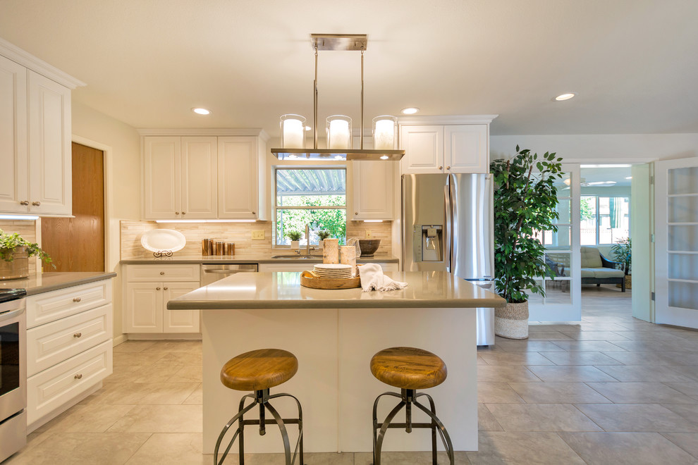 Example of a large transitional l-shaped porcelain tile open concept kitchen design in Phoenix with an undermount sink, raised-panel cabinets, white cabinets, quartz countertops, beige backsplash, porcelain backsplash, stainless steel appliances and an island
