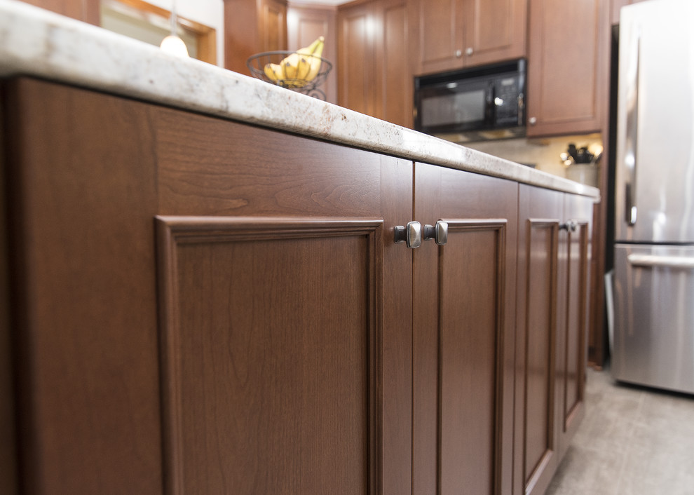 Inspiration for a large timeless l-shaped vinyl floor and beige floor eat-in kitchen remodel in Baltimore with an undermount sink, shaker cabinets, medium tone wood cabinets, granite countertops, beige backsplash, ceramic backsplash, stainless steel appliances, an island and white countertops