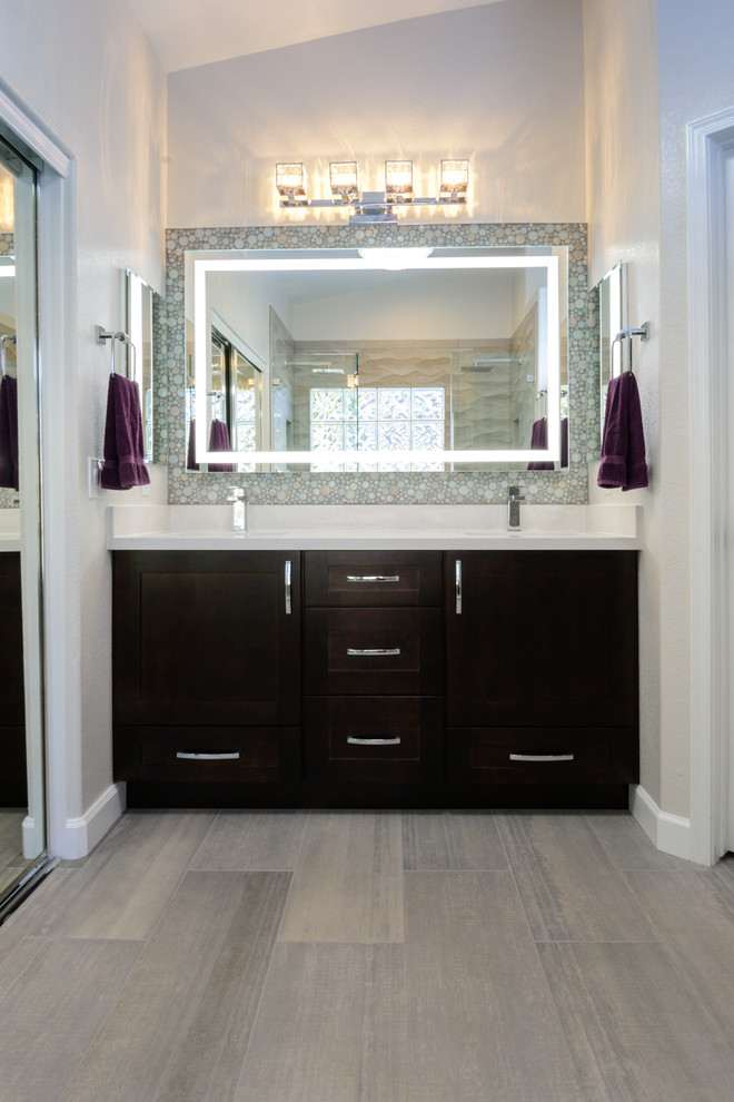 Inspiration for a mid-sized transitional master bathroom in Phoenix with shaker cabinets, brown cabinets, a double shower, a two-piece toilet, gray tile, ceramic tile, grey walls, ceramic floors, an undermount sink, solid surface benchtops, grey floor and a hinged shower door.