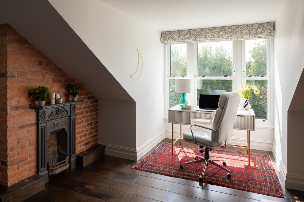 This is an example of a large scandi study in Sussex with white walls, dark hardwood flooring, a standard fireplace, a metal fireplace surround, a freestanding desk and brown floors.