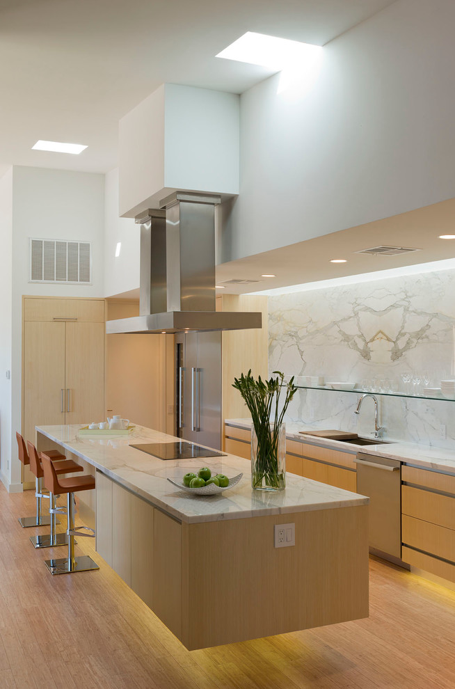 Design ideas for a large contemporary galley eat-in kitchen in Austin with flat-panel cabinets, light wood cabinets, white splashback, marble splashback, an undermount sink, quartzite benchtops, stainless steel appliances, light hardwood floors, with island and brown floor.