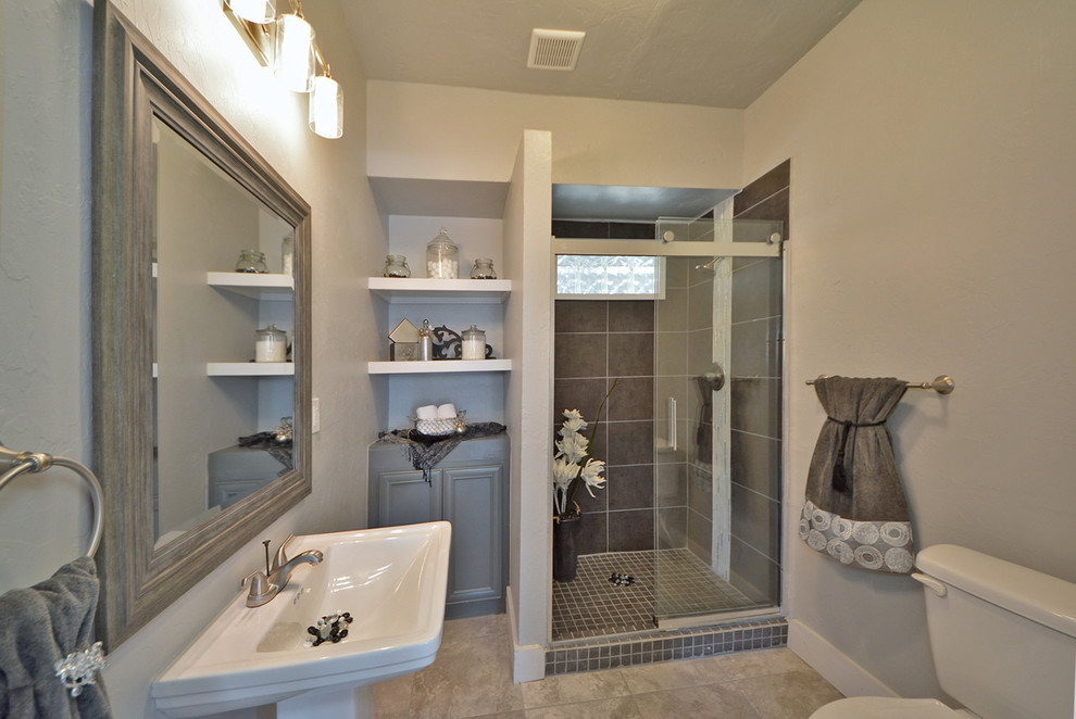 Photo of a midcentury bathroom in Oklahoma City with a pedestal sink, open cabinets, grey cabinets, a corner shower, grey walls, ceramic floors and gray tile.